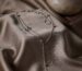 Silver beaded lariat necklace with a long beaded drop on taupe silk